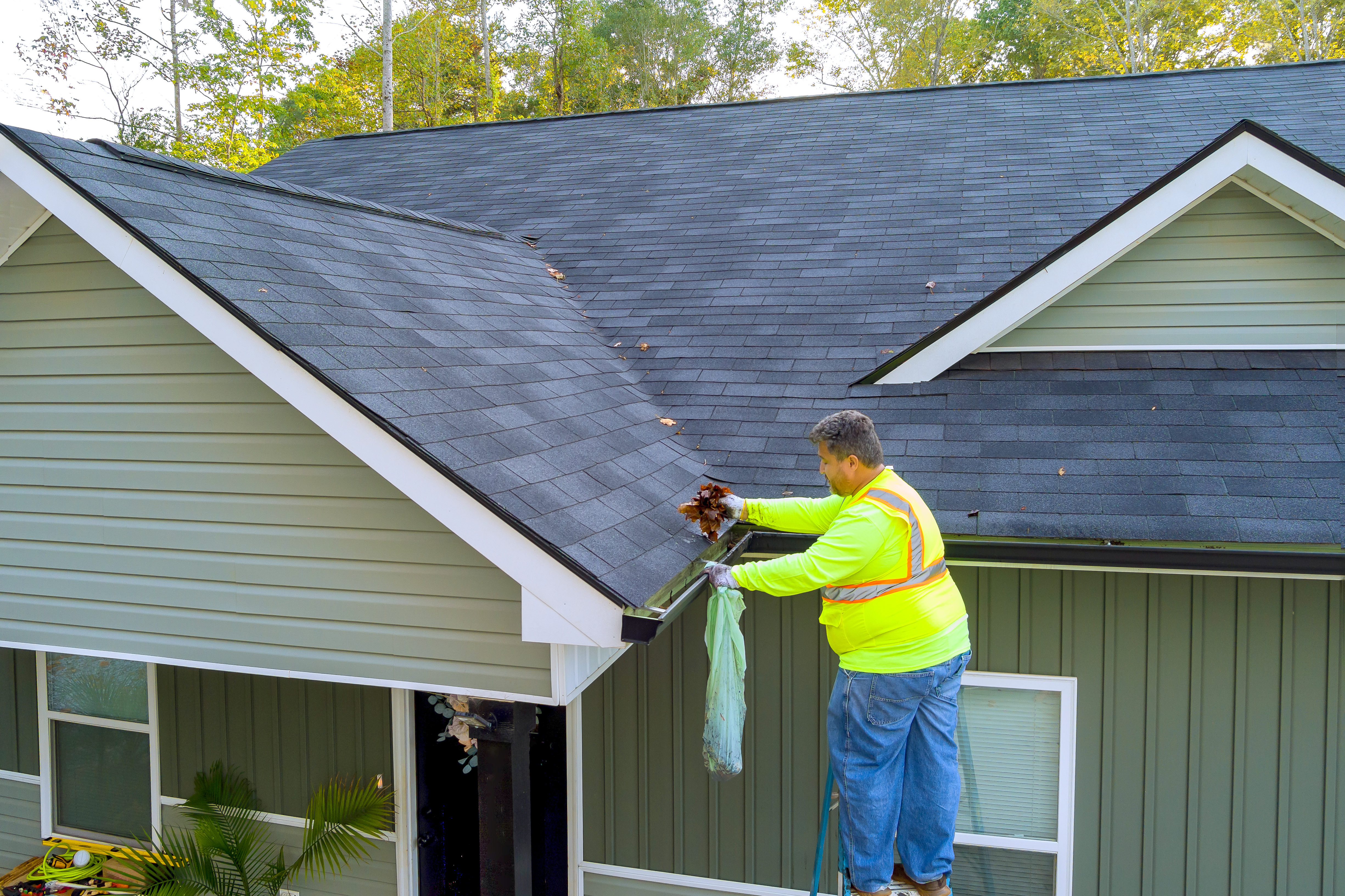 Worker removing dirt and debris from roof gutter